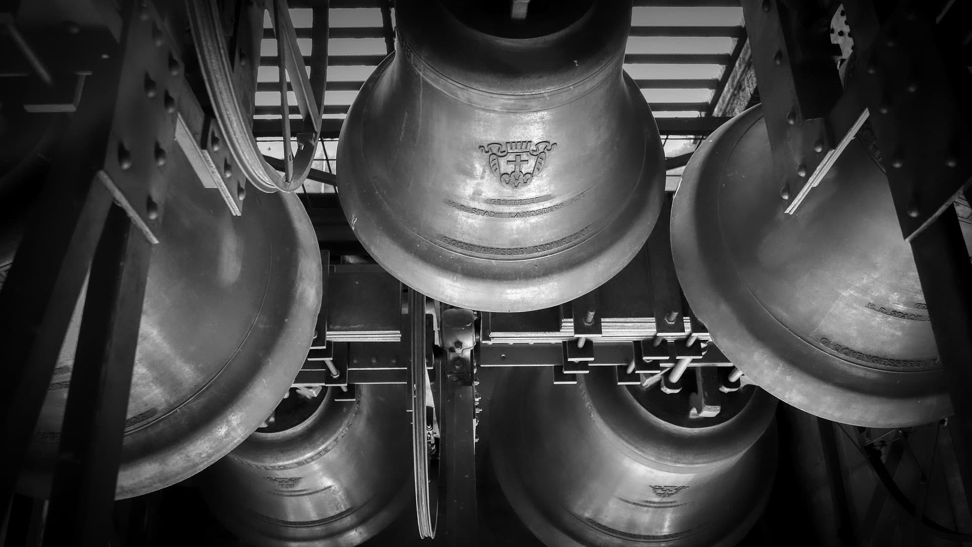 Cluster of aged bronze bells suspended inside a bell tower